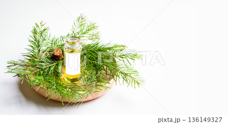 Essential fir oil bottle surrounded by branches on wooden plate Banner with copy space Essential fir oil bottle surrounded by branches on wooden plate Banner with copy space 136149327