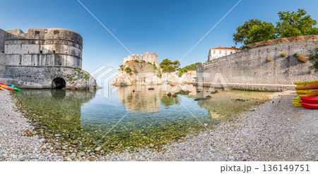 View of small water bay near old city of Dubrovnik. Ancient fort Lovrijenac near small harbor with boats. Sunny day. 136149751