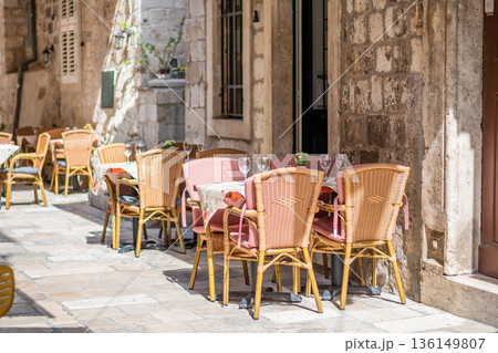 Table and chairs at the restaurant in narrow street are prepared for guests and tourist. Old city of Dubrovnik, Croatia. Table and chairs at the restaurant in narrow street are prepared for guests and tourist. Old city of Dubrovnik, Croatia. 136149807