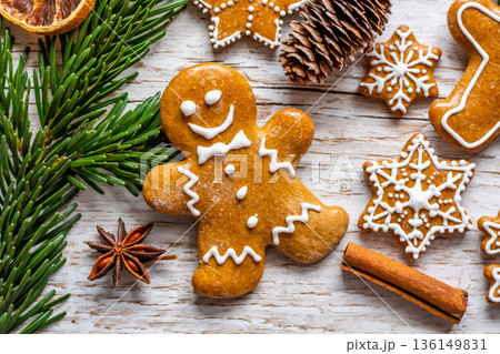 Christmas gingerbread and sweets are placed on wooden desk. Cookies and sweet food in shape of stars and snow flakes. Winter theme, rustic style. Pine trees on the side. Candy stick and other spice. Christmas gingerbread and sweets are placed on wooden desk. Cookies and sweet food in shape of stars and snow flakes. Winter theme, rustic style. Pine trees on the side. Candy stick and other spice. 136149831