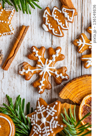 Christmas gingerbread and sweets are placed on wooden desk. Cookies and sweet food in shape of stars and snow flakes. Winter theme, rustic style. Pine trees on the side. Candy stick and other spice. Christmas gingerbread and sweets are placed on wooden desk. Cookies and sweet food in shape of stars and snow flakes. Winter theme, rustic style. Pine trees on the side. Candy stick and other spice. 136149836