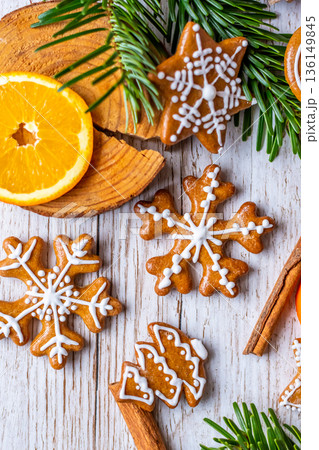 Christmas gingerbread and sweets are placed on wooden desk. Cookies and sweet food in shape of stars and snow flakes. Winter theme, rustic style. Pine trees on the side. Candy stick and other spice. 136149845