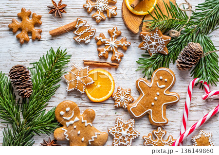 Christmas gingerbread and sweets are placed on wooden desk. Cookies and sweet food in shape of stars and snow flakes. Winter theme, rustic style. Pine trees on the side. Candy stick and other spice. Christmas gingerbread and sweets are placed on wooden desk. Cookies and sweet food in shape of stars and snow flakes. Winter theme, rustic style. Pine trees on the side. Candy stick and other spice. 136149860