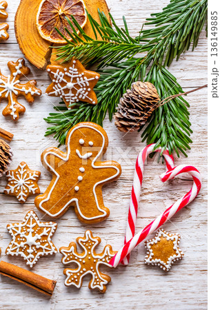Christmas gingerbread and sweets are placed on wooden desk. Cookies and sweet food in shape of stars and snow flakes. Winter theme, rustic style. Pine trees on the side. Candy stick and other spice. Christmas gingerbread and sweets are placed on wooden desk. Cookies and sweet food in shape of stars and snow flakes. Winter theme, rustic style. Pine trees on the side. Candy stick and other spice. 136149885