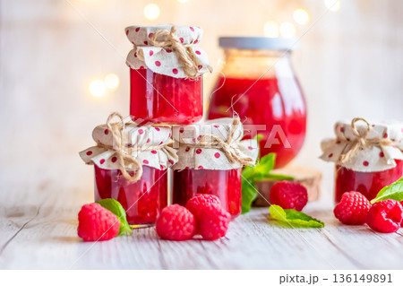 Raspberry marmalade in small glasses is placed on wooden desk. Homemade jam from fresh raspberries. Fresh and healthy cooking. 136149891