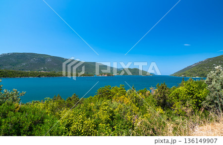 View of beautiful Croatia coast near Makarska. Blue sea with white beach. Isles in the background. Summer weather, blue sky. View of beautiful Croatia coast near Makarska. Blue sea with white beach. Isles in the background. Summer weather, blue sky. 136149907