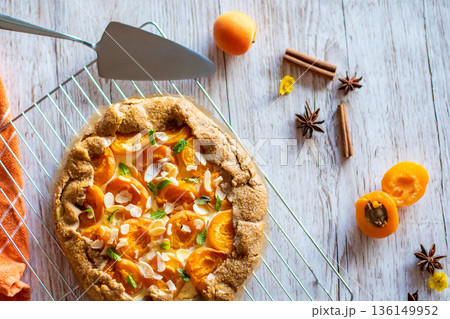 Apricot galette pie cake placed on wooden background with cooking tools on the side Apricot galette pie cake placed on wooden background with cooking tools on the side 136149952