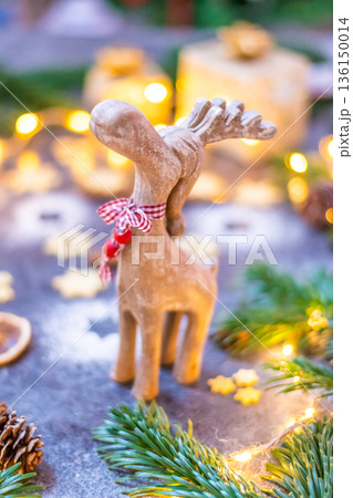 Christmas reindeer wooden toy statue with pine tree, cone and winter light in background. 136150014
