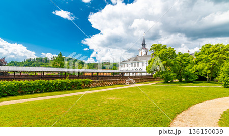 Lysice castle, Czech Republic. Famous baroque castle built in 14th century. Beautiful formal garden, palm trees and flowers. Promenade near the castle. Sunny day, dramatic clouds before storm. 136150039