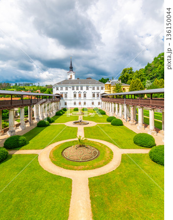 Lysice castle, Czech Republic. Famous baroque castle built in 14th century. Beautiful formal garden, palm trees and flowers. Promenade near the castle. Sunny day, dramatic clouds before storm. Lysice castle, Czech Republic. Famous baroque castle built in 14th century. Beautiful formal garden, palm trees and flowers. Promenade near the castle. Sunny day, dramatic clouds before storm. 136150044