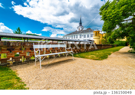 Lysice castle, Czech Republic. Famous baroque castle built in 14th century. Beautiful formal garden, palm trees and flowers. Promenade near the castle. Sunny day, dramatic clouds before storm. 136150049