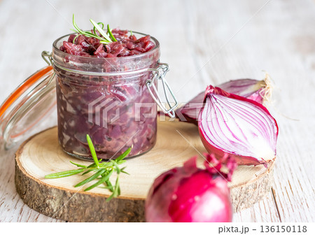 Red onion marmalade placed on wooden trunk with wood texture background. Jam from onion is delicious part of French cuisine. Homemade jam in transparent glass, vibrant colors, soft light. 136150118