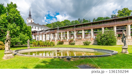 Lysice castle, Czech Republic. Famous baroque castle built in 14th century. Beautiful formal garden, palm trees and flowers. Promenade near the castle. Sunny day, dramatic clouds before storm. 136150294