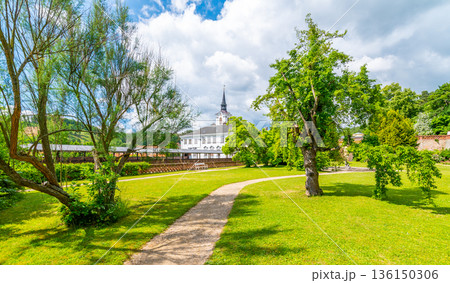 Lysice castle, Czech Republic. Famous baroque castle built in 14th century. Beautiful formal garden, palm trees and flowers. Promenade near the castle. Sunny day, dramatic clouds before storm. 136150306