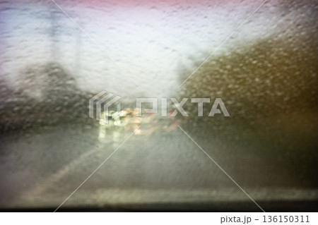 Car driving through blurred rain drops on windshield Car driving through blurred rain drops on windshield 136150311