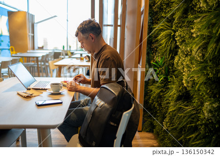 Man in cafe working on laptop 136150342