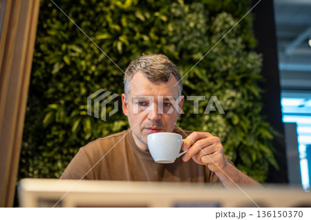 Man drinking coffee in modern cafe Man drinking coffee in modern cafe 136150370