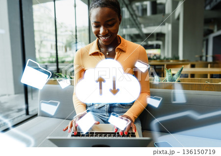 Woman using laptop in cafe with cloud symbols around her during daytime in the city 136150719