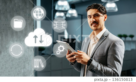 Professional man using tablet in office with digital icons around him showing cloud technology Professional man using tablet in office with digital icons around him showing cloud technology 136150813