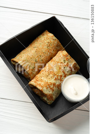 Two freshly cooked crepes served with a small cup of cream Two freshly cooked crepes served with a small cup of cream 136150883