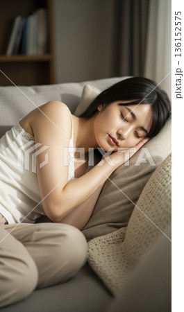ソファでクッションを抱いて気持ちよさそうに昼寝をする日本人女性 136152575