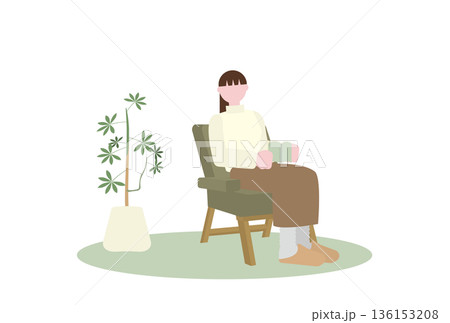 植物のある部屋の一人がけソファで本を読む女性 136153208