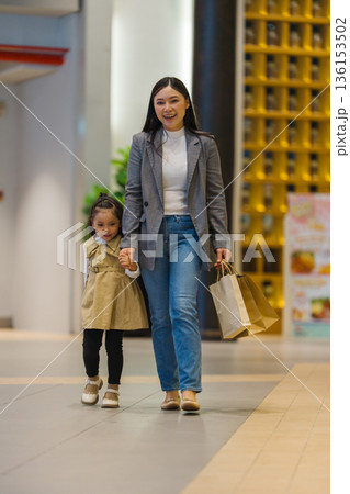 mother and child girl walking with shopping bag in a department store mother and child girl walking with shopping bag in a department store 136153502