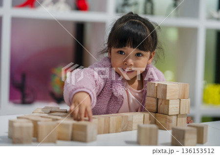 preschool child girl concentrating on building tower with wooden block preschool child girl concentrating on building tower with wooden block 136153512