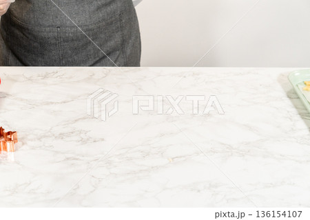 A close up from a wifes perspective of a cookie cutter and sugar cookie dough prepared for shaping 136154107