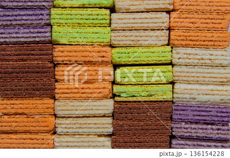 colorful wafer biscuits stacked in rows. Crispy sweet snack pattern with various flavors like chocolate, strawberry, and vanilla. Creative food background colorful wafer biscuits stacked in rows. Crispy sweet snack pattern with various flavors like chocolate, strawberry, and vanilla. Creative food background 136154228