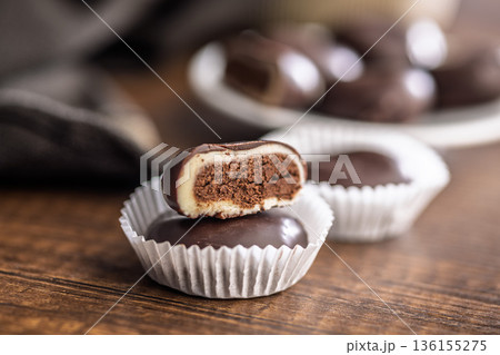 Dark chocolate truffles in the shape of coffee beans on wooden table. 136155275