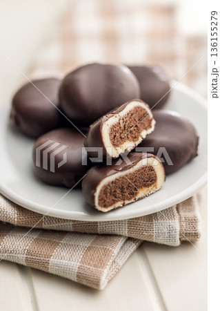 Dark chocolate truffles in the shape of coffee beans on plate on white table. 136155279
