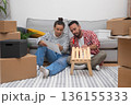 Crafting Home Together: A happy couple in a new apartment builds a modern wooden shelf unit surrounded by boxes, enhancing their home decor during the move 136155333