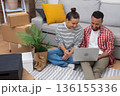 Designing Dreams: Young homeowners or renters in a new apartment, laptop amidst boxes, shape their ideal living space, shop online, or manage their move 136155336