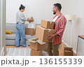 Smiling young couple engages in packing and unpacking boxes as they transition into their mortgaged home 136155339