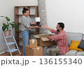 delighted young family, husband and wife, enjoys the process of moving into their new residence, placing a lamp on an empty shelf and embracing the joy of relocation 136155340