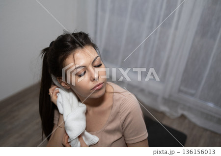 Woman With Closed Eyes Wiping Her Face With a White Towel After Exercise Woman With Closed Eyes Wiping Her Face With a White Towel After Exercise 136156013