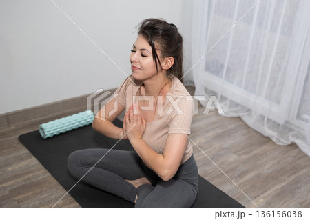 Practicing Yoga Indoors While Sitting on a Mat in a Well-Lit Room Practicing Yoga Indoors While Sitting on a Mat in a Well-Lit Room 136156038