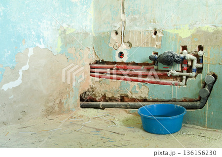 Old wall with exposed plumbing pipes during home renovation. Plumbing repair in old house, broken wall and pipes visible. Plumbing Renovation and Wall Repairs 136156230