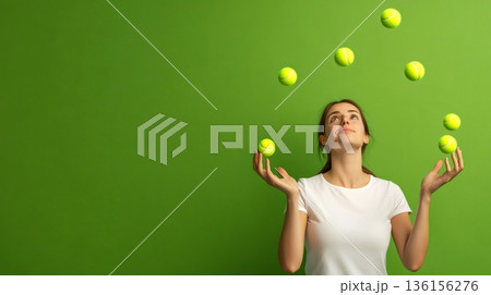 Woman skillfully juggling tennis balls against a green background, symbolizing multitasking and time management. Concept of balancing work, deadlines, and stress in chaotic environments 136156276