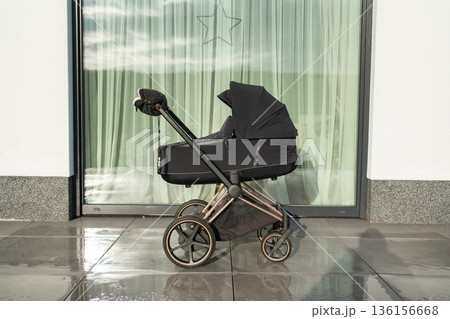Modern baby stroller standing near large window. Minimal family lifestyle and parenting concept. 136156668