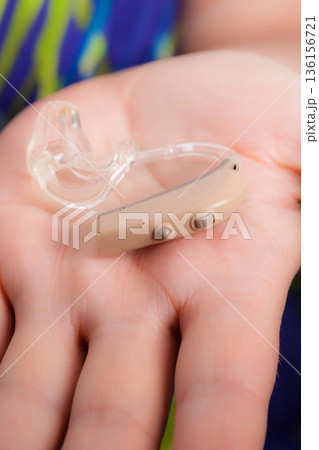 senior person holding hearing aid closeup senior person holding hearing aid closeup 136156721