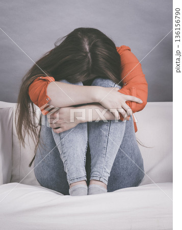 Worried woman sitting on sofa Worried woman sitting on sofa 136156790