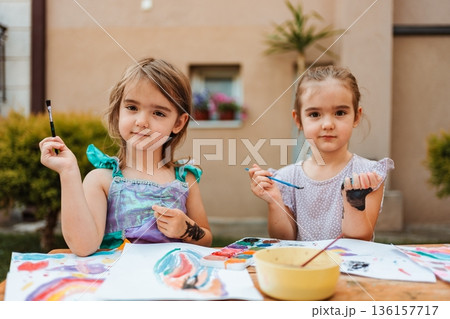 Two preschool age girls painting with watercolors in the backyard 136157717