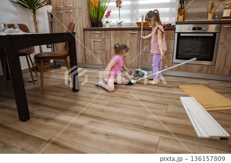 Two children joyfully cleaning the kitchen on a sunny afternoon Two children joyfully cleaning the kitchen on a sunny afternoon 136157809