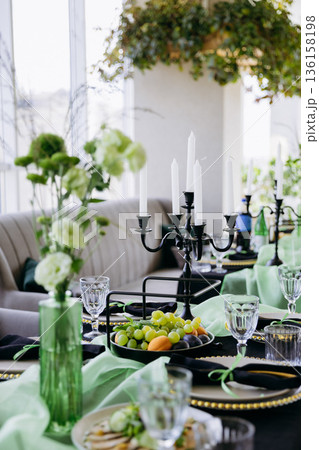 Luxury green and black dinner table setting with candles, flowers and glassware Luxury green and black dinner table setting with candles, flowers and glassware 136158198