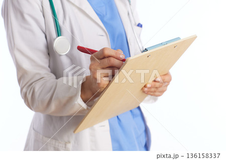 Female Doctor Writing Medical Notes on Clipboard 136158337