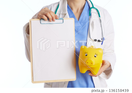 Medical Professional Holding Clipboard and Yellow Piggy Bank Medical Professional Holding Clipboard and Yellow Piggy Bank 136158439