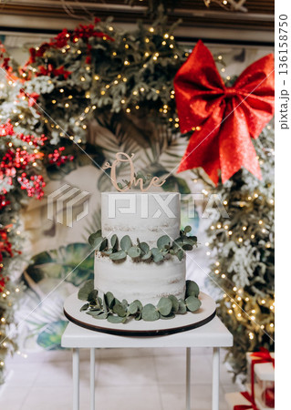 First birthday cake with One topper and eucalyptus, Christmas wreath backdrop, copy space 136158750