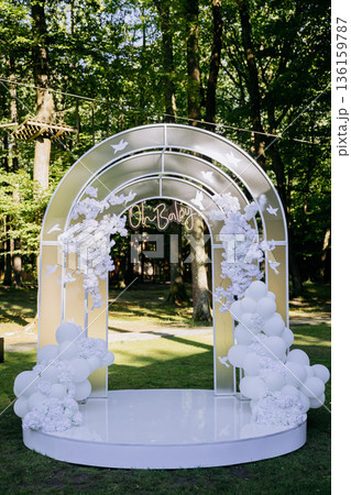 White balloon and flower arch for baby shower outdoors in park, elegant event backdrop 136159787